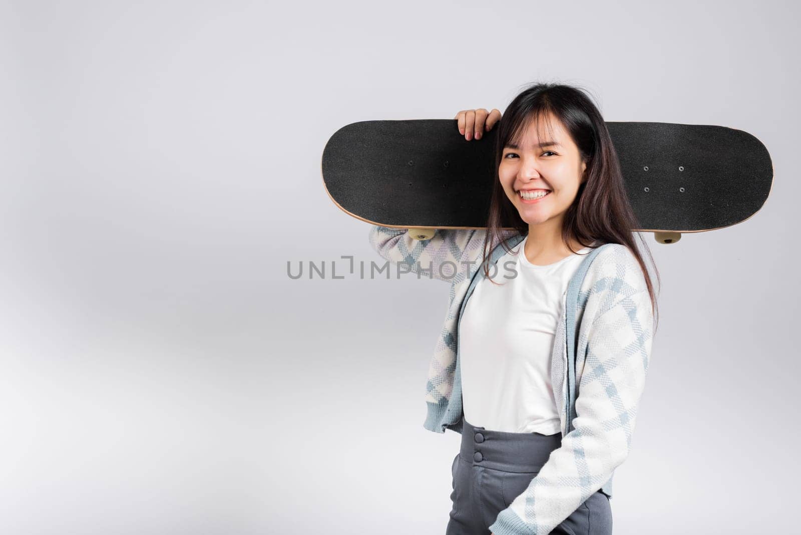 Smiling happy woman holding skateboard on shoulder, Happy Asian beautiful young female excited hold hands longboard, studio shot isolated on white background with copy space, sport extreme