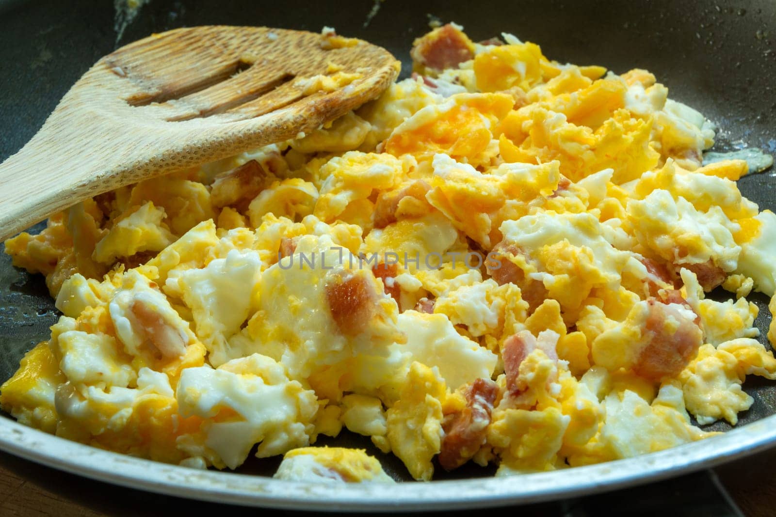 Scrambled eggs with bacon in a pan, close up