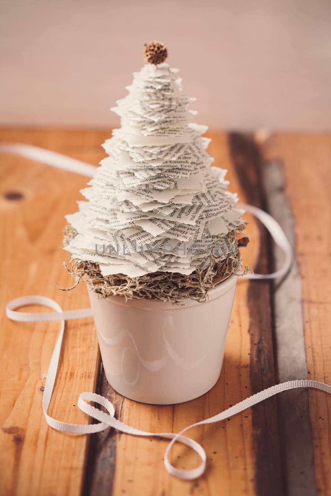 Mini DIY paper tree Christmas decoration with natural moss on wooden background