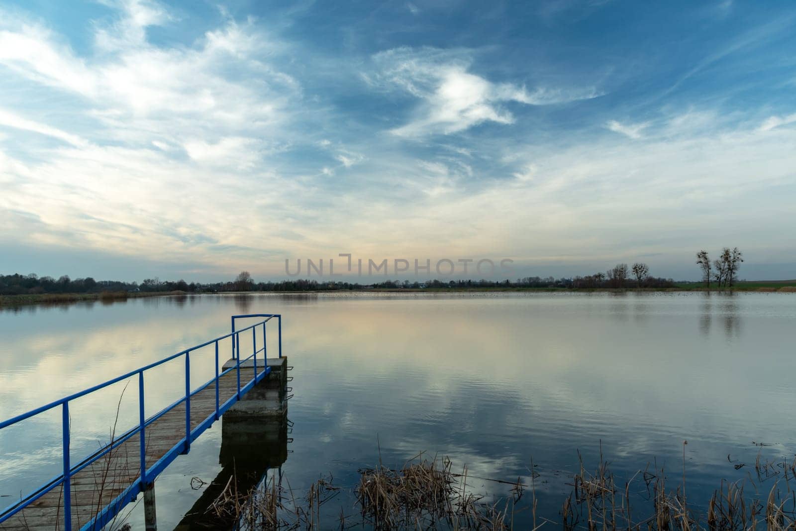 A narrow jetty on a calm lake and clouds, Staw, Poland