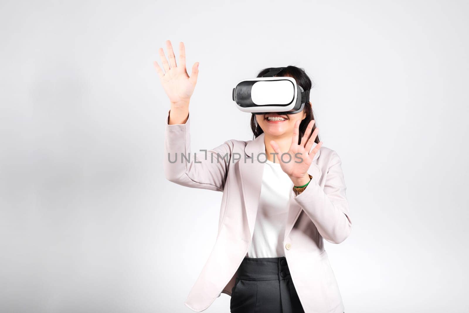 Smiling woman confidence excited wear VR headset device touching air during virtual reality experience isolated white background, Asian happy portrait female playing video game studio shot, copy space