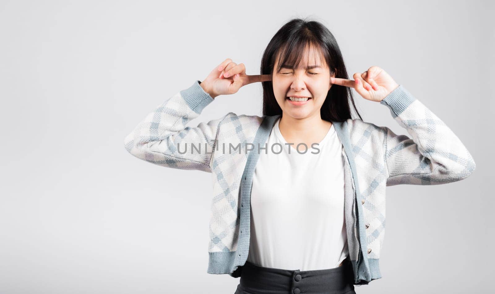 Woman bad mood pain her closed ears with finger and close eyes, Asian beautiful young female covers ears for loud noise, studio shot isolated on white background with copy space