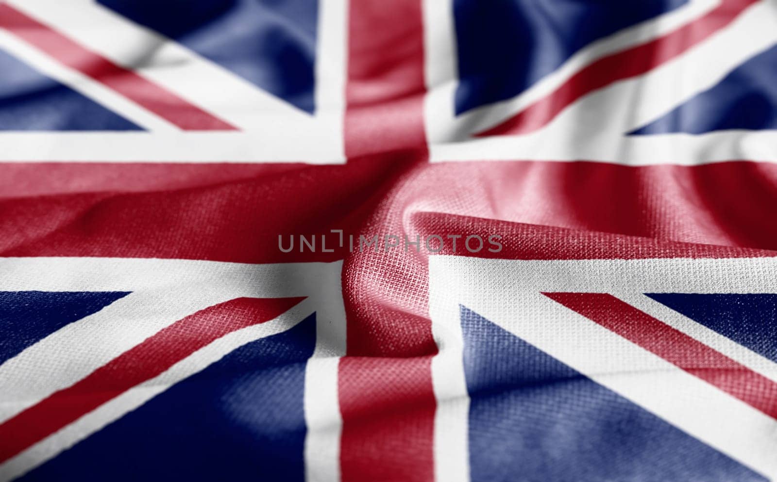 Close up of the United Kingdom flag on a ruffled fabric. Curves and folds of the satin fabric with texture. Selective focus and depth of field. Democracy and politics. South american country.