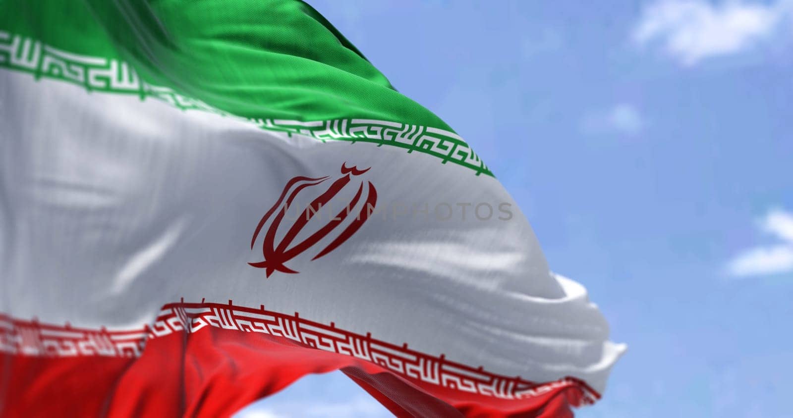 Detail of the national flag of Iran waving in the wind on a clear day. Islamic republic. Patriotism. Western asian country. Selective focus.