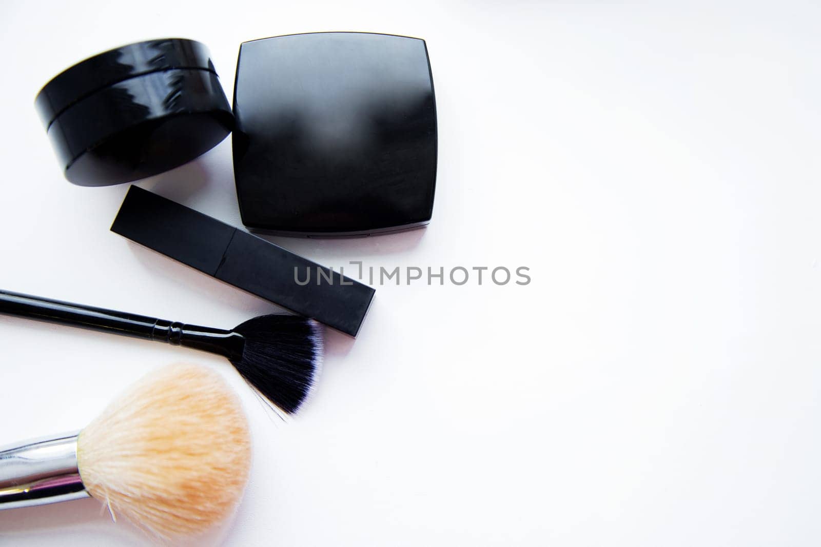 Lipstick and face powder and brush lying together on white background with place for text. High quality photo