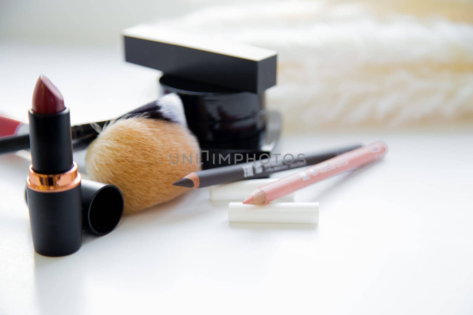 Two pencils for eyes and lips, lipstick, brushes, blush lie together on white background. High quality photo