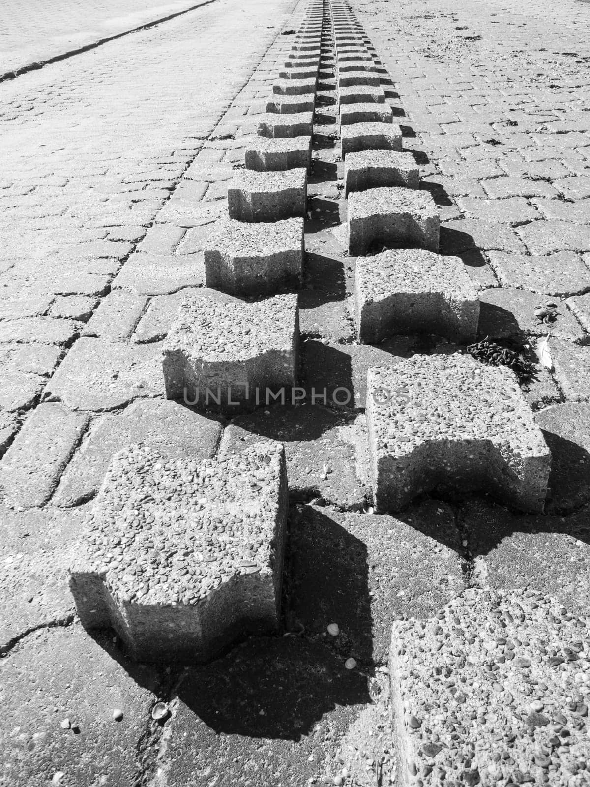 Monochrome wide angle view of small breakwater running into the distance on the beach promenade on the German North Sea coast.