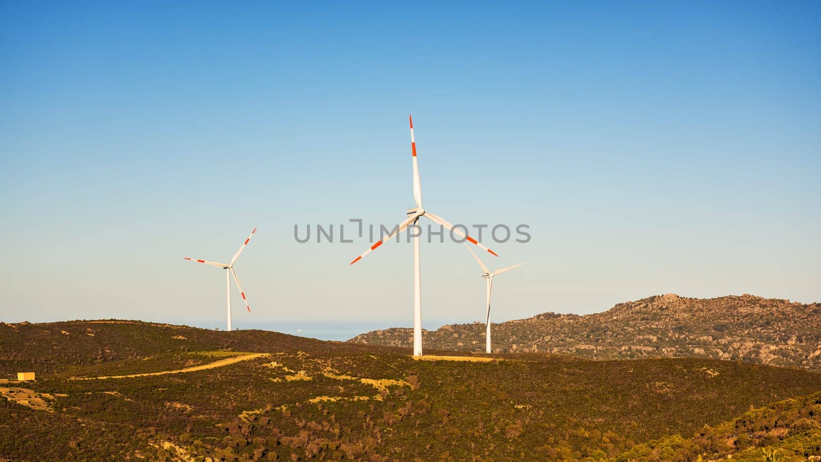 Wind turbines on a beautiful sunset sky in a mountain wind farm in Sardinia. Renewable energy concept, green energy generation. Energy industry.