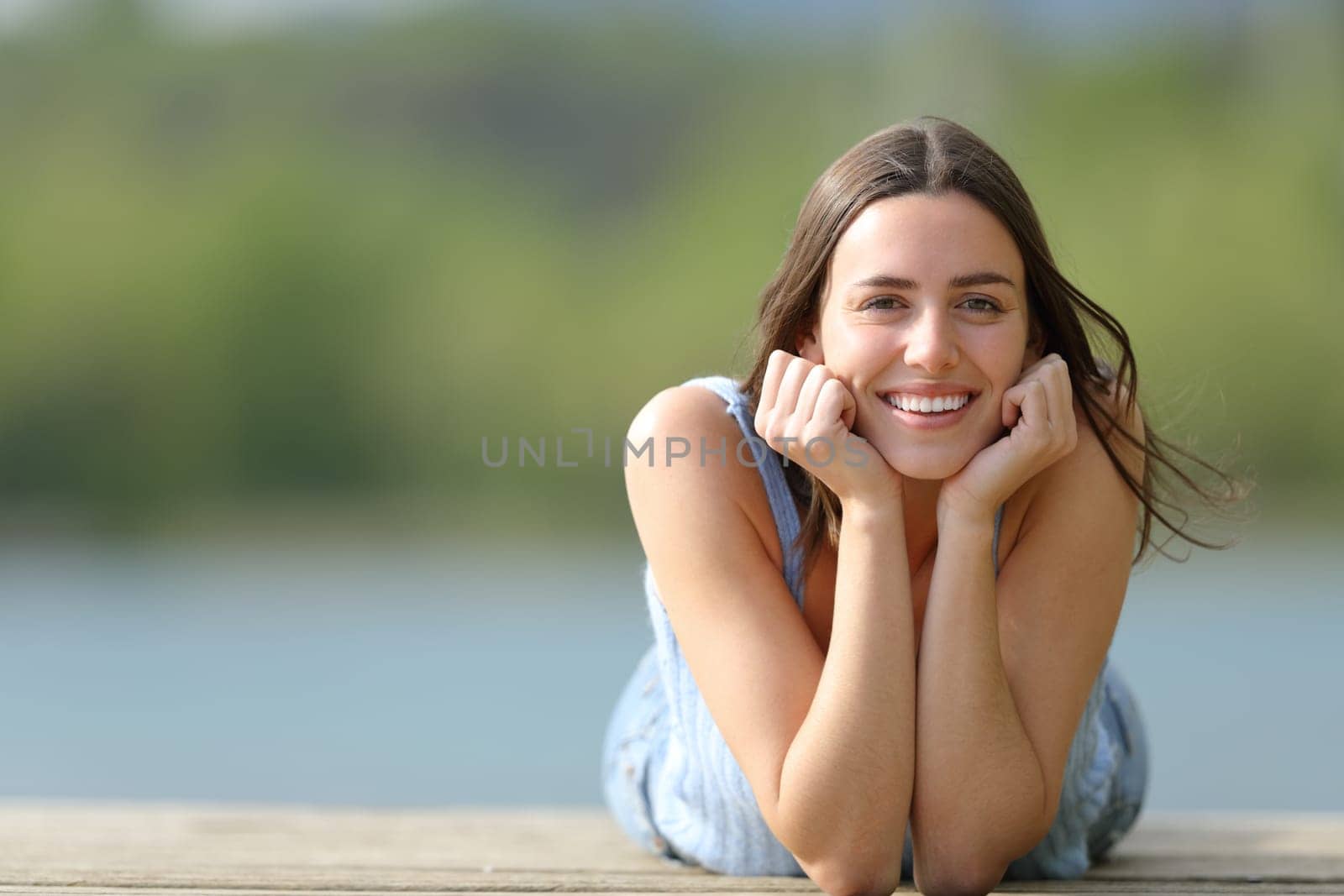 Happy woman looking at camera lying on pier
