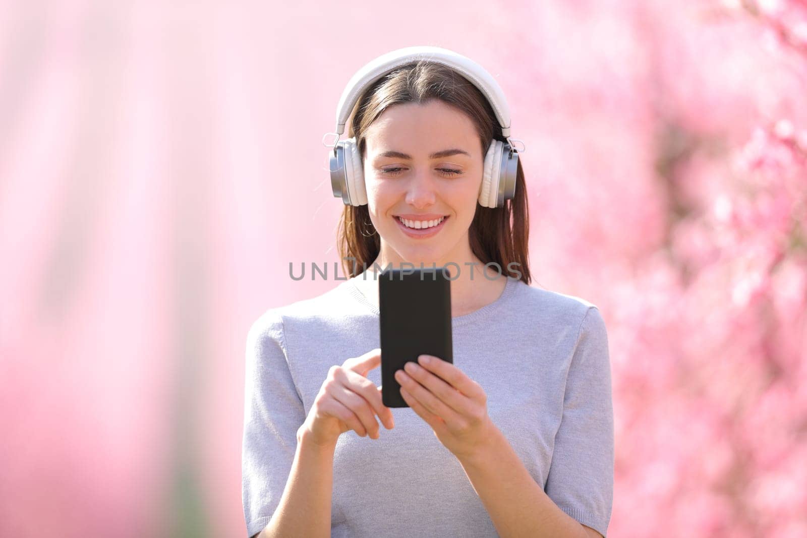 Happy woman walking listening to music through a field