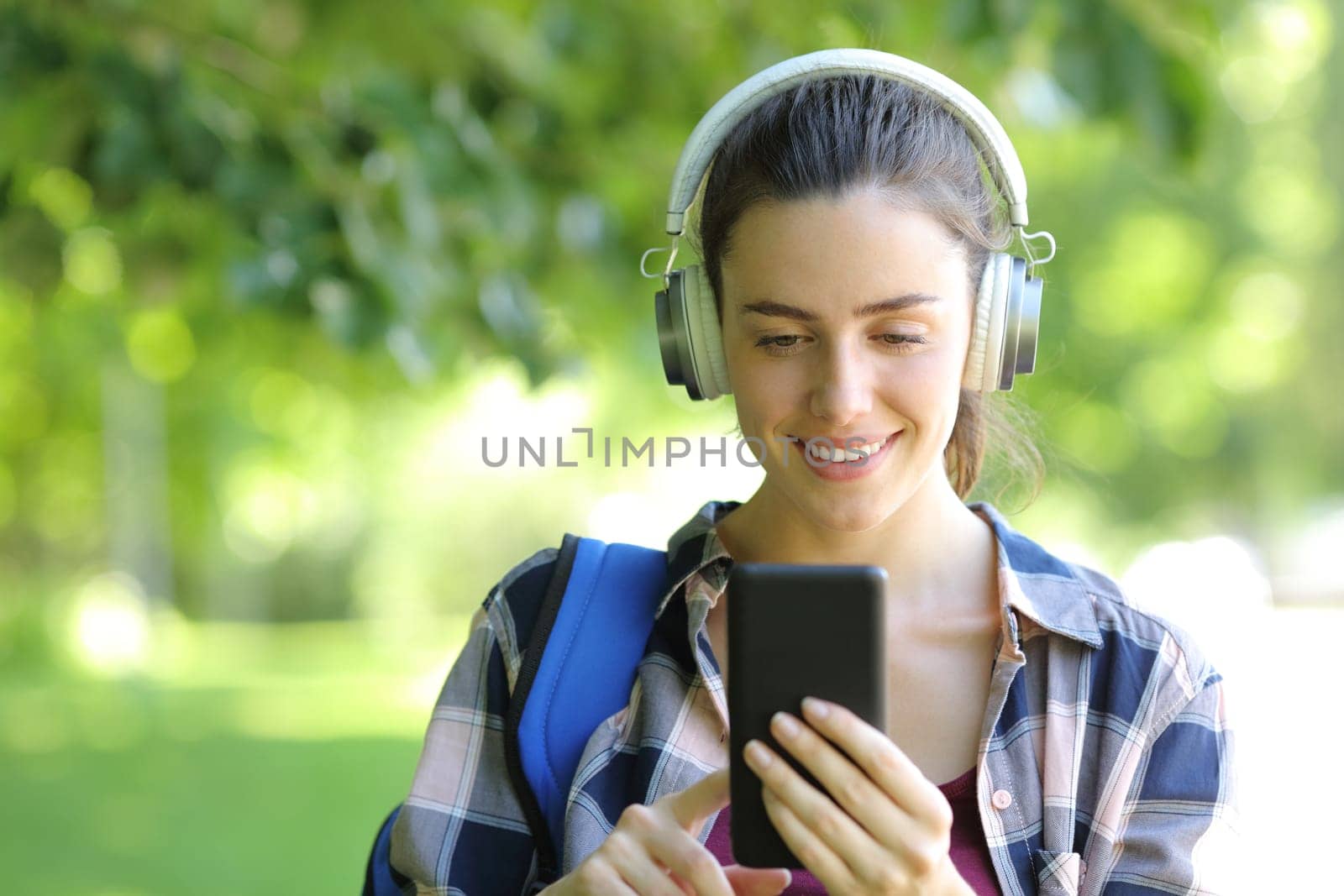 Happy student listening to music outdoors