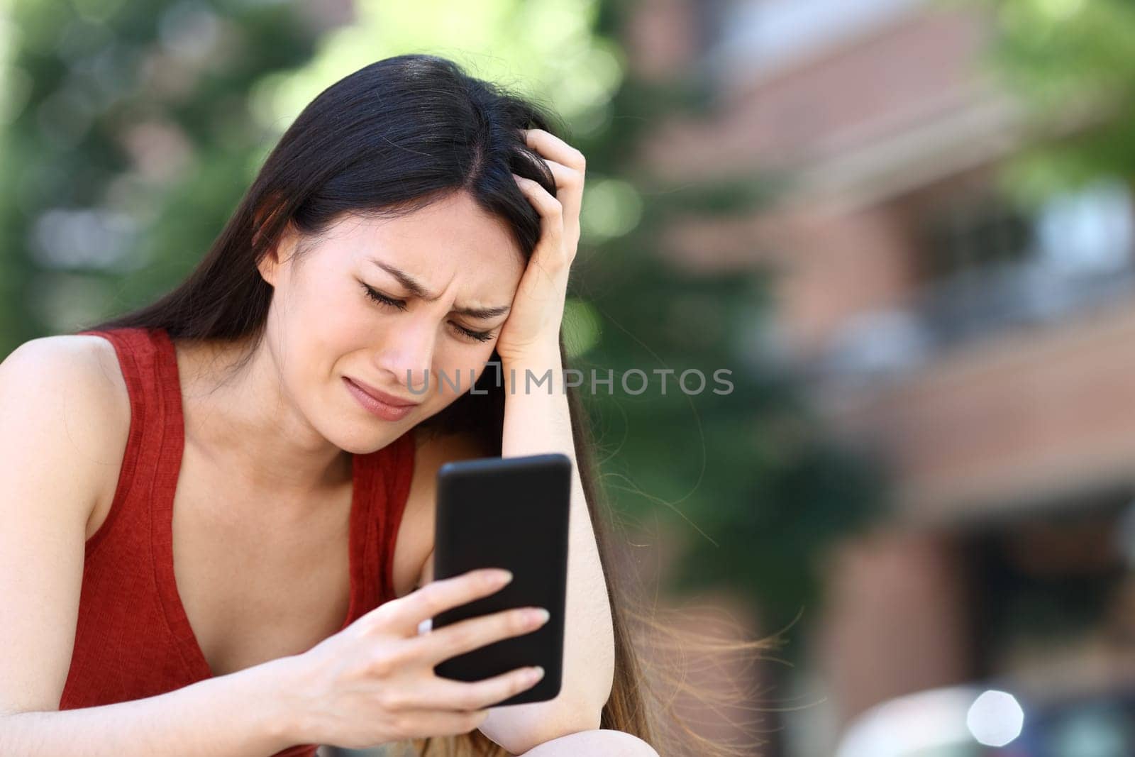 Worried asian woman checking smartphone