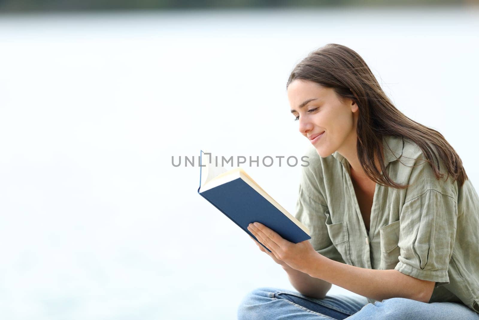 Happy woman reading a book in a lake