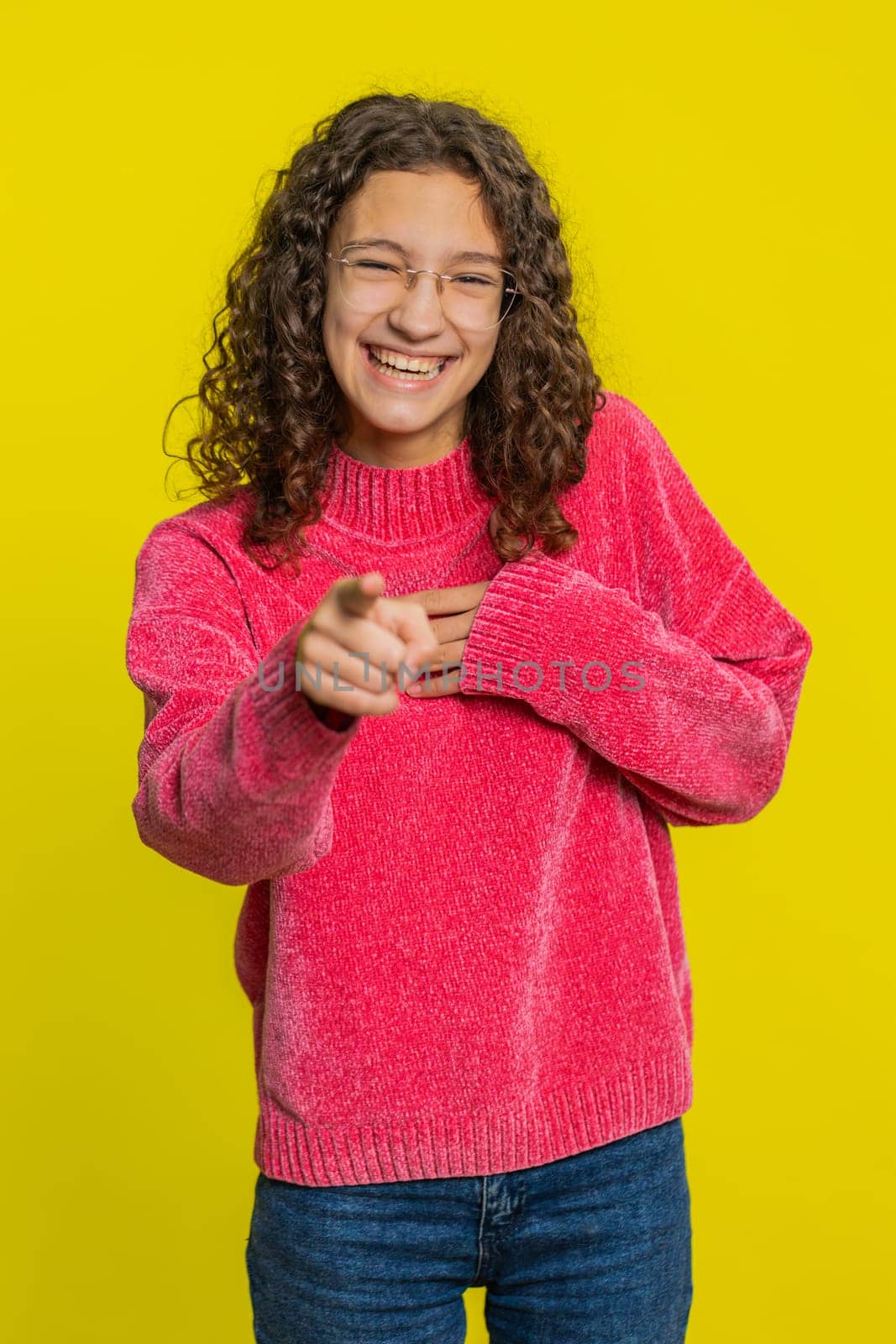 Caucasian girl pointing finger to camera, laughing out loud, taunting making fun of ridiculous appearance, funny joke anecdote, bullying, abuse. Young teen child isolated on yellow background indoors