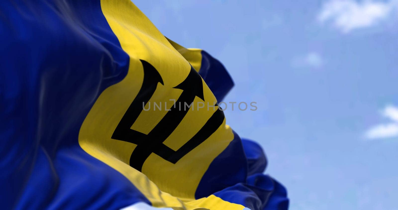 Detail of the national flag of Barbados waving in the wind on a clear day. Barbados is an island in the Lesser Antilles of the West Indies, in the Caribbean region of the Americas. Selective focus.