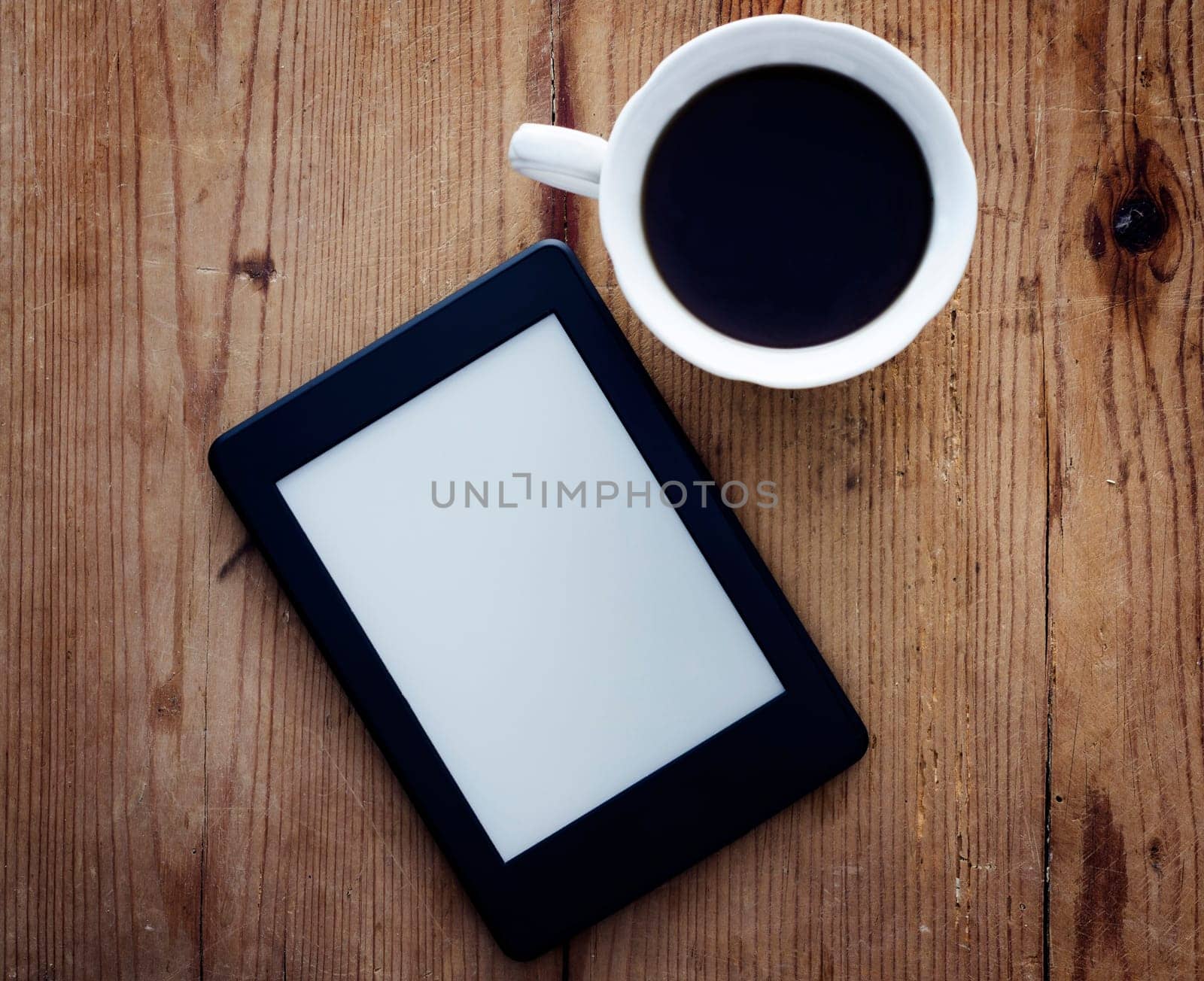 E-book reader and coffee cup on wooden table