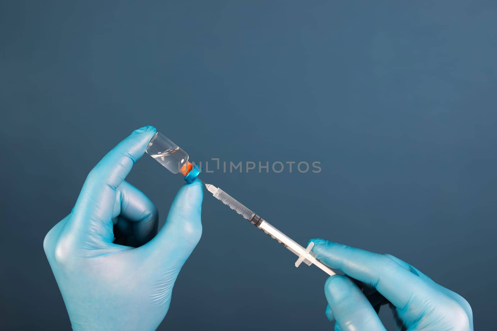 COVID-19 coronavirus vaccine. Vaccination concept. Doctor's hand in blue gloves hold medicine vaccine vial bottle and syringe.