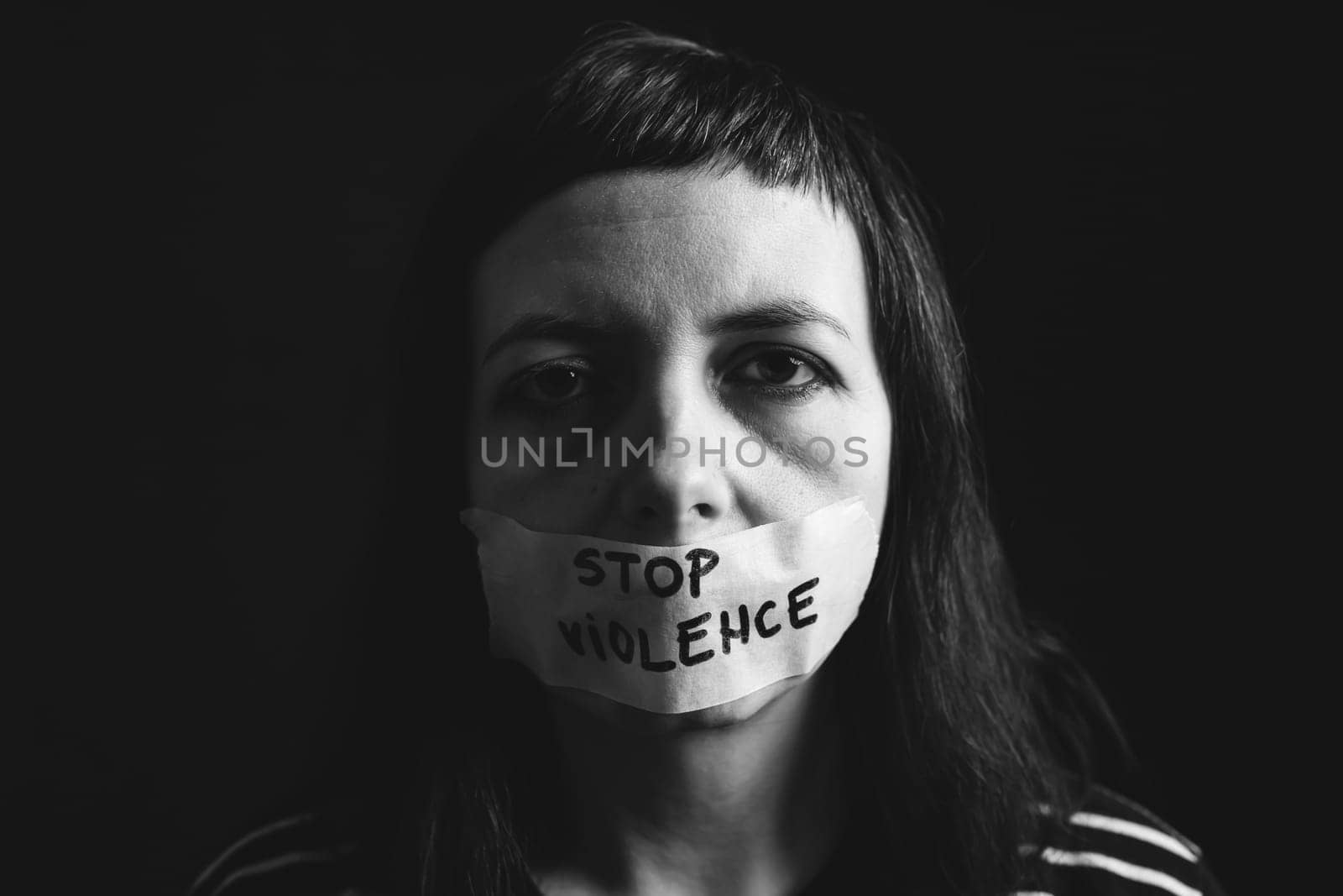 Women violence and abused concept. Stop domestic violence against women and human trafficking.Woman with tape on mouth and stop violence text
