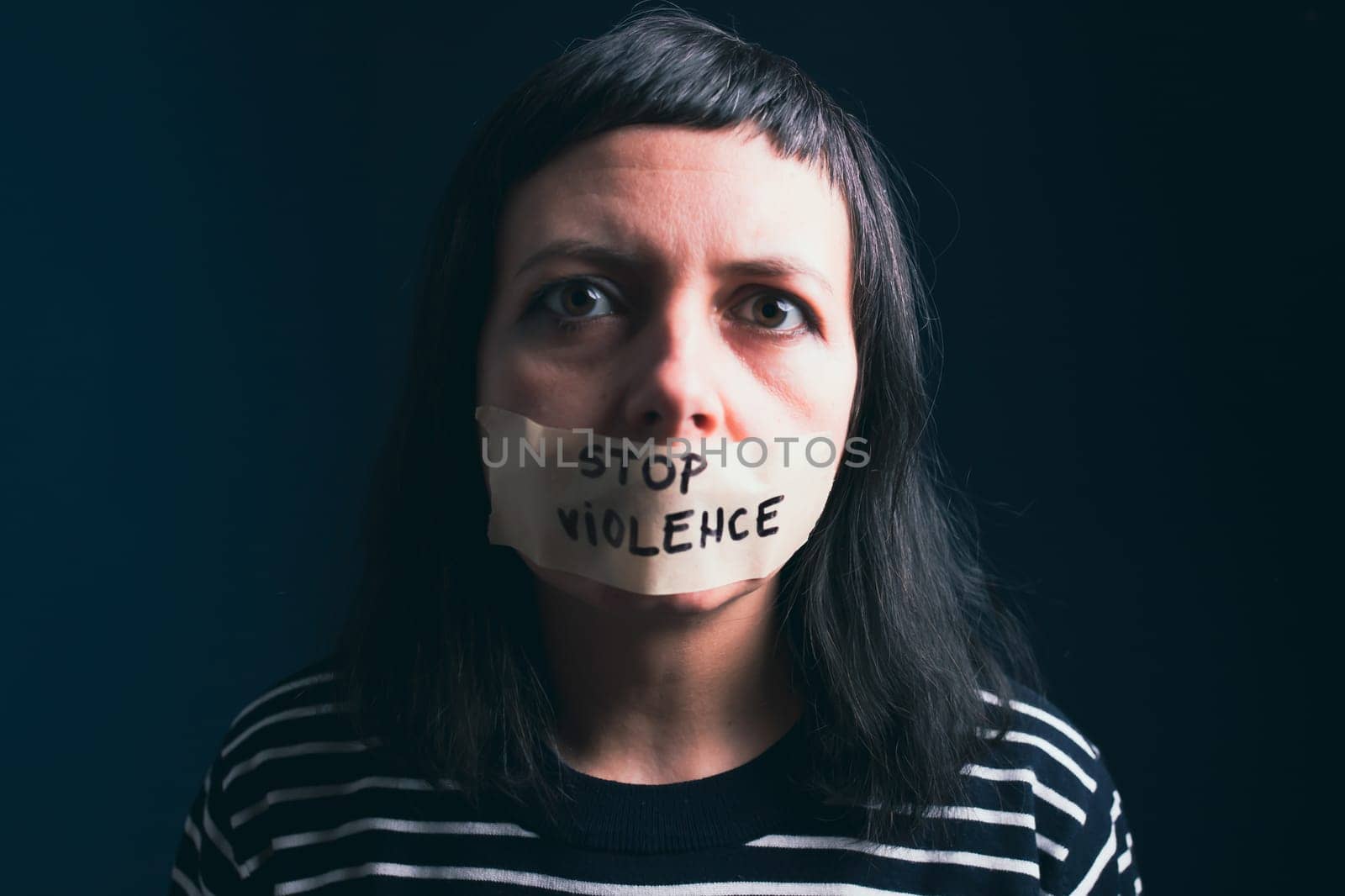 Women violence and abused concept. Stop domestic violence against women and human trafficking.Woman with tape on mouth and stop violence text