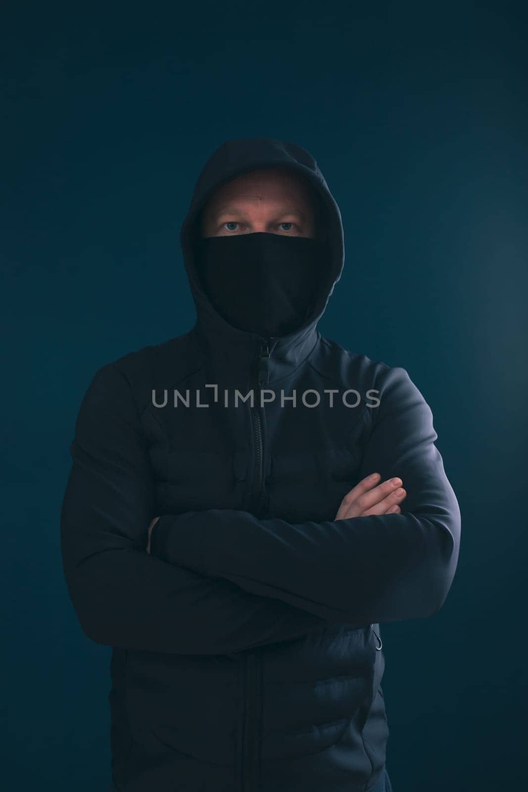 Scary man hiding in the shadows, with the face and identity hidden with the hood. Concept for fear, mystery, danger, crime, stalker