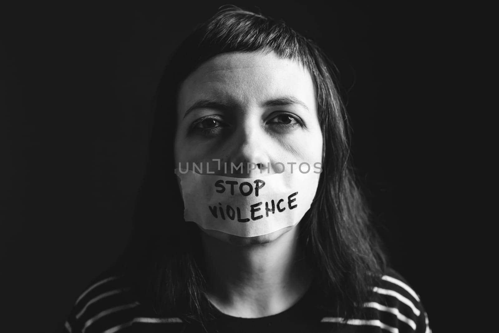 Women violence and abused concept. Stop domestic violence against women and human trafficking.Woman with tape on mouth and stop violence text