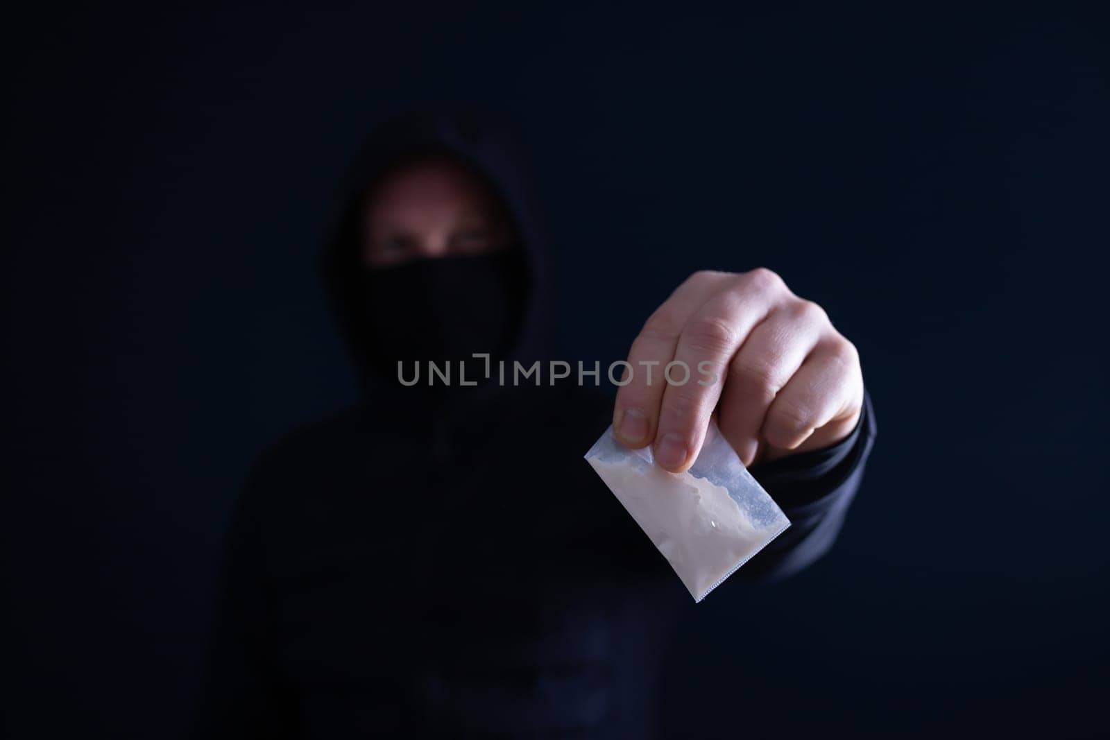 Hand of addict man holding a dose of cocaine or heroine. Concept of drug dealer, drug trafficking, crime, addiction and sale.