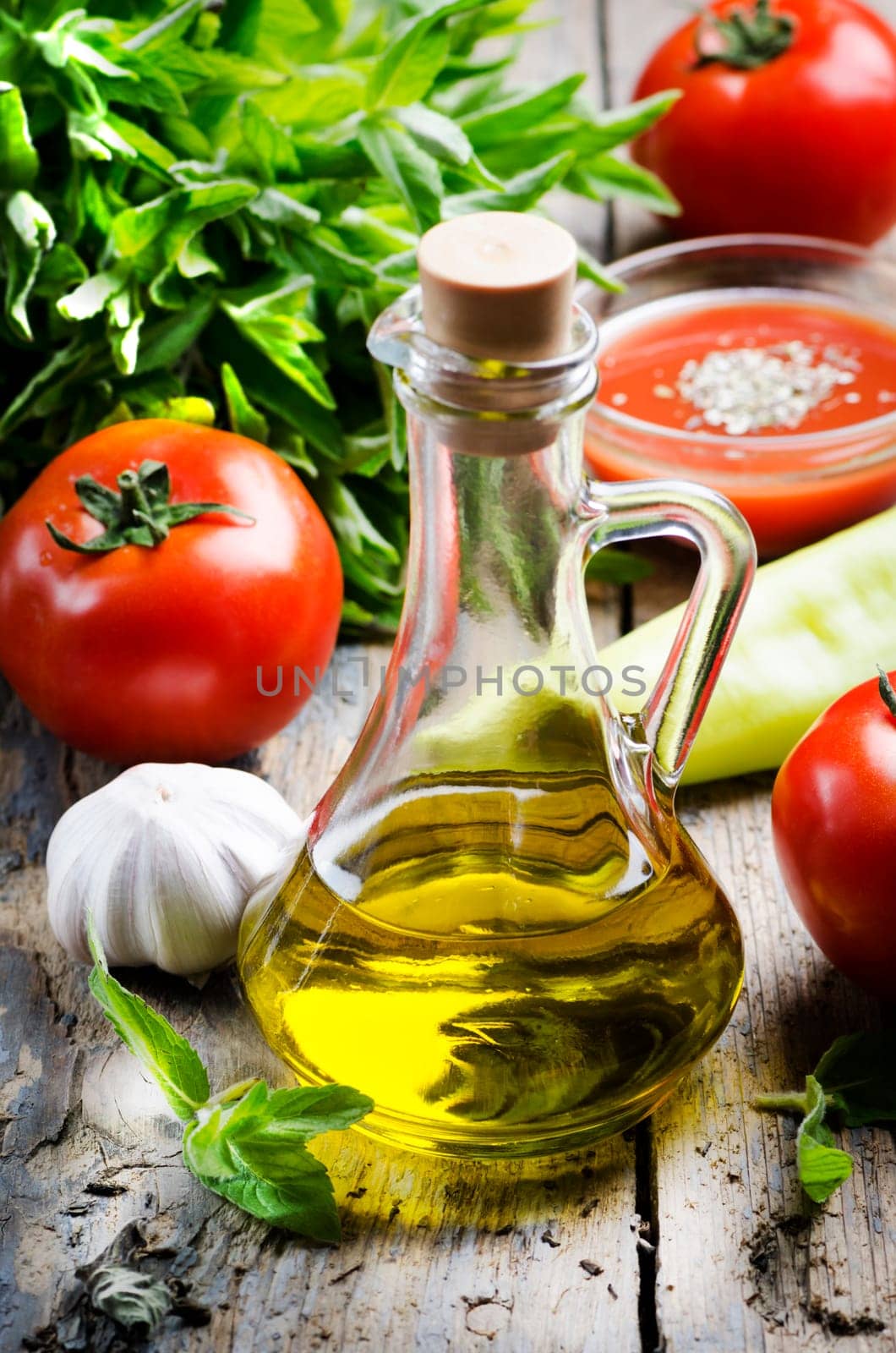 Olive oil, tomato and herbs on rustic wooden table
