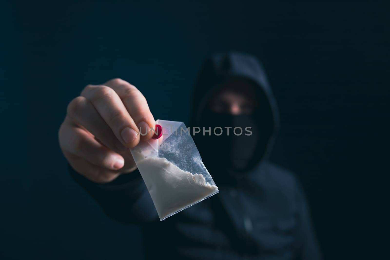 Hand of addict man holding a dose of cocaine or heroine. Concept of drug dealer, drug trafficking, crime, addiction and sale.