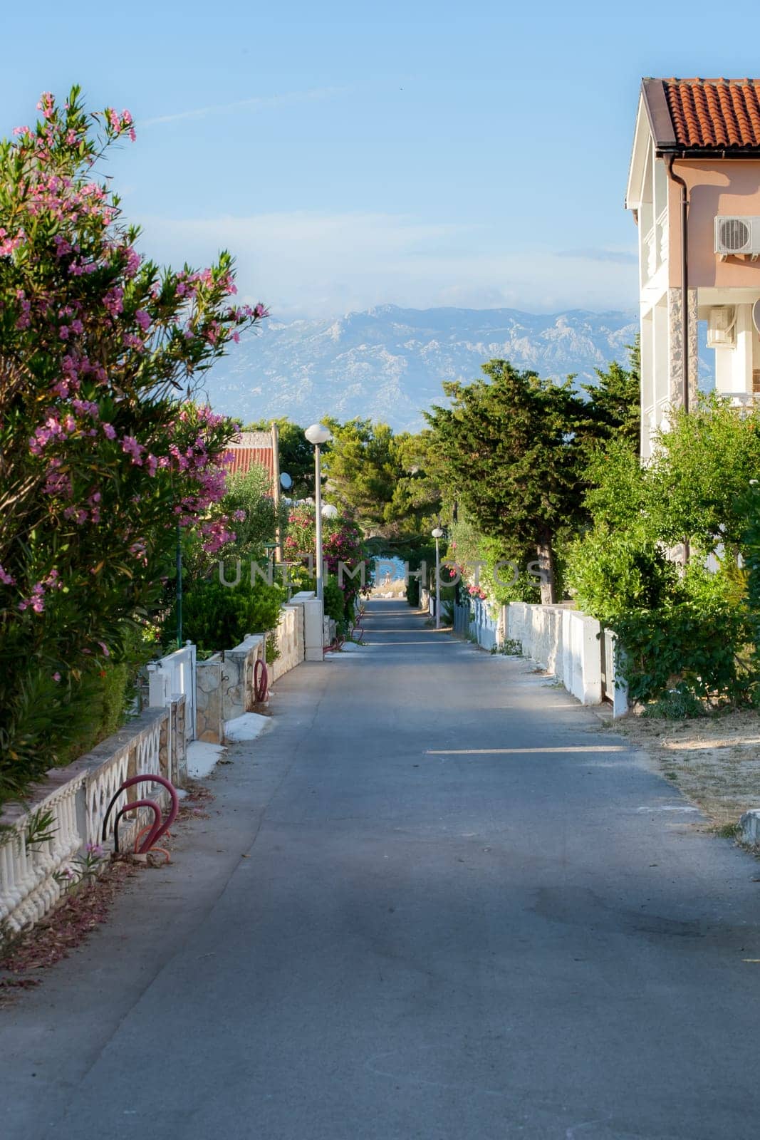 A small alley towards the sea in the apartment complex Lučica on the island of Vir, Croatia. View of the sea and the mountains.