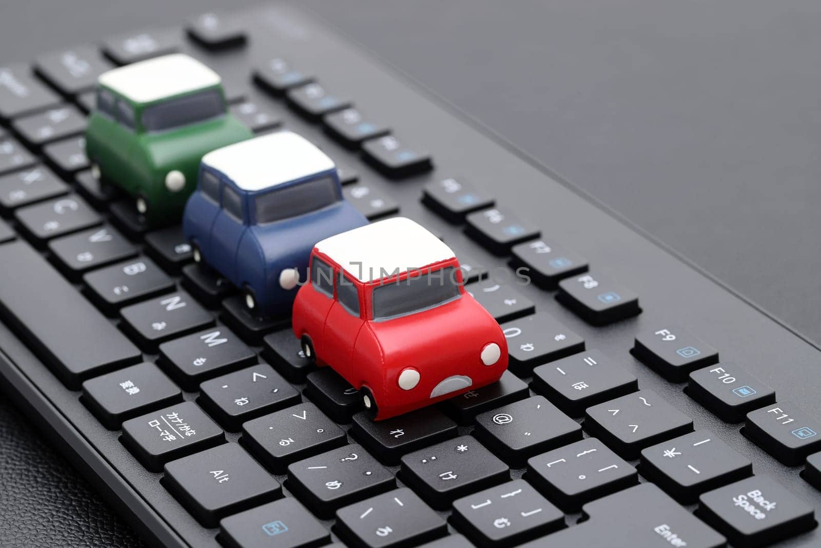KAGAWA, JAPAN - FEBRUARY 23, 2022 - Small toy car on Alphabetics and Japanese hiragana typing keyboard.