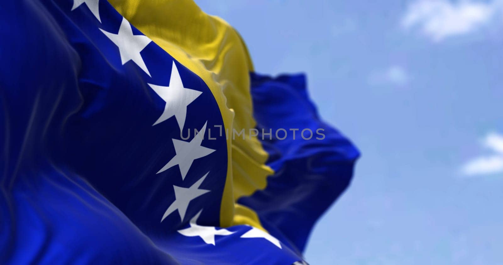 Detail of the national flag of Bosnia and Herzegovina waving in the wind on a clear day. Democracy and politics. Selective focus. Bosnia, is a country at the crossroads of south and southeast Europe