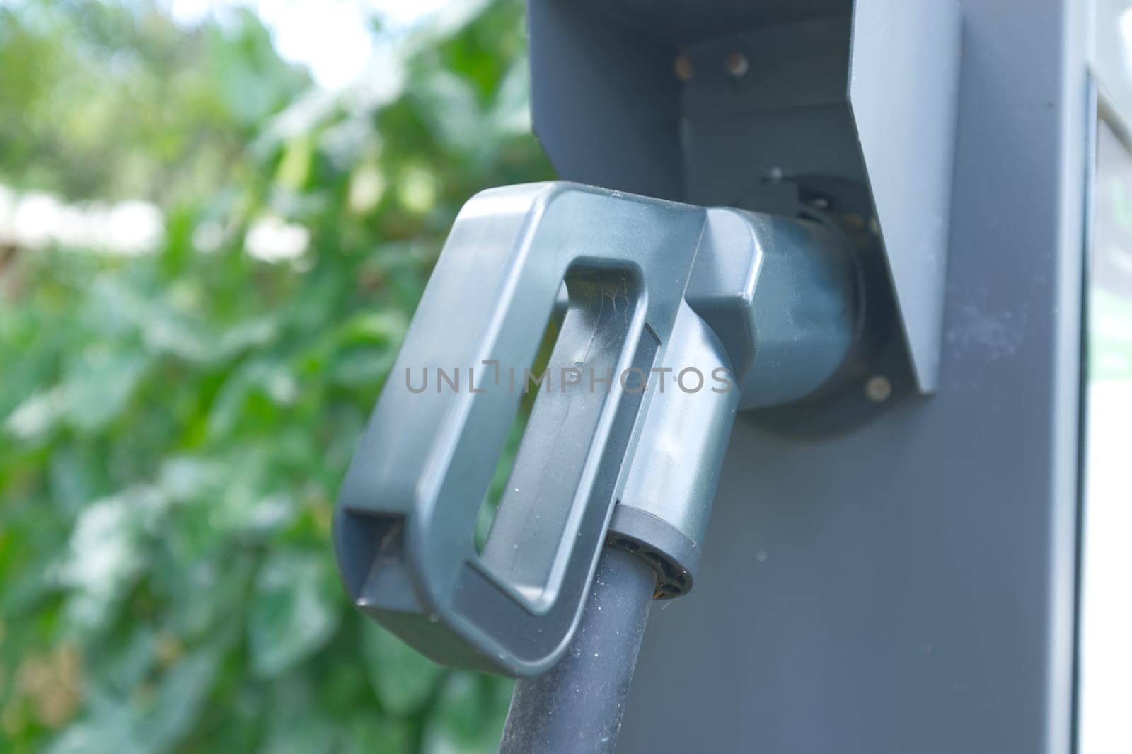 EV Car or Electric car at charging station with the power cable supply plugged .