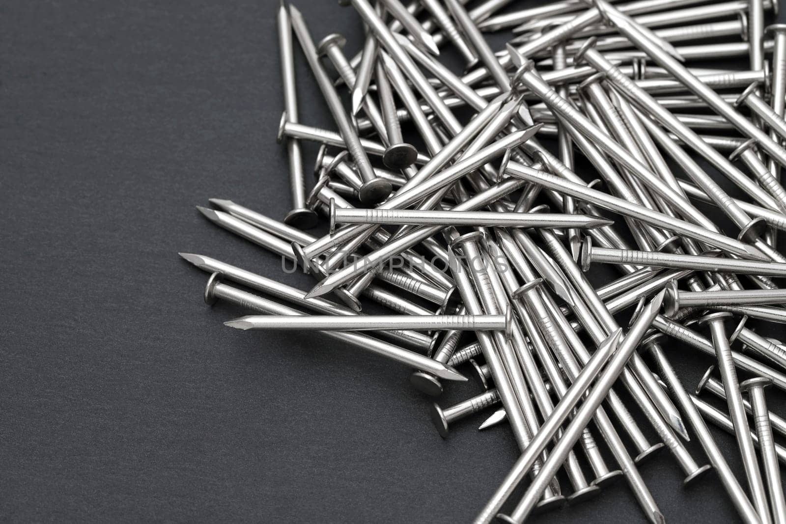 Pile of silver metallic nails on black background