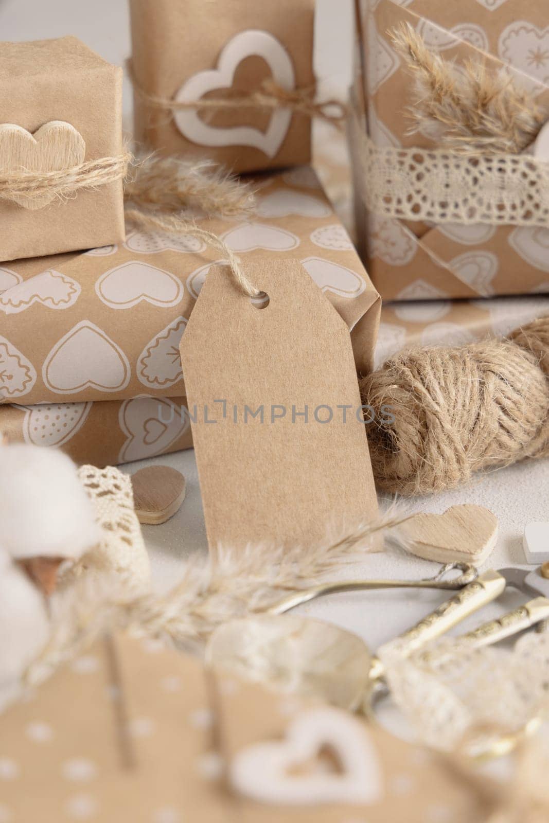 Valentines wrapped presents with vertical gift tag close up. Spring scene with blank label. Rustic, cottage chic or bohemian mockup, copy space
