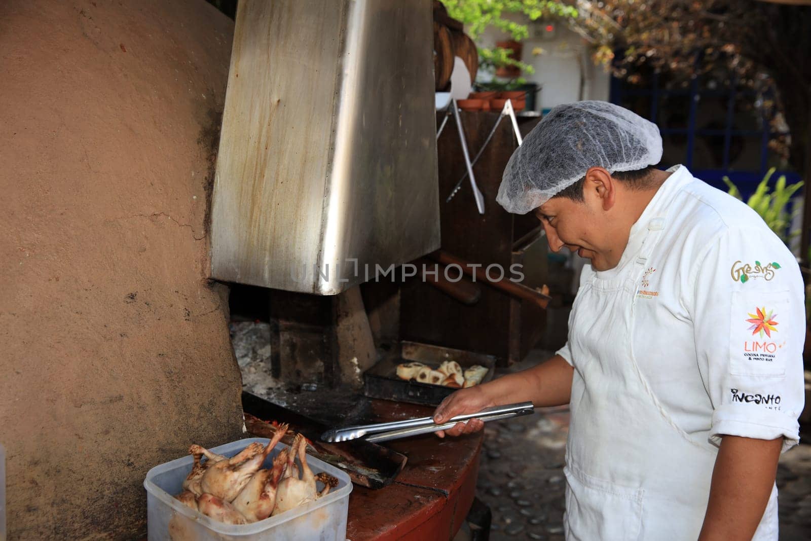 Man at the Restaurant Pachapacha in Cusco grills Guinea Pig – the traditional Meal in Peru