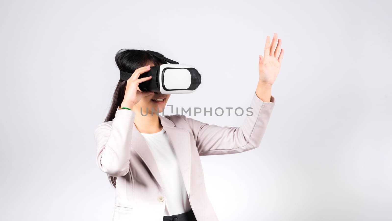 Smiling woman confidence excited wear VR headset device touching air during virtual reality experience isolated white background, Asian happy portrait female playing video game studio shot, copy space