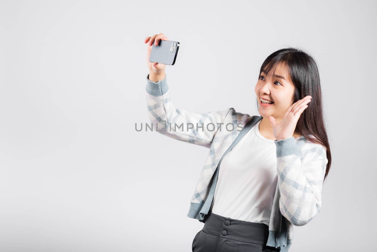 Woman excited holding smartphone to shooting selfie photo front camera studio shot isolated white background, happy young female smiling taking photography by mobile phone on mobile phone