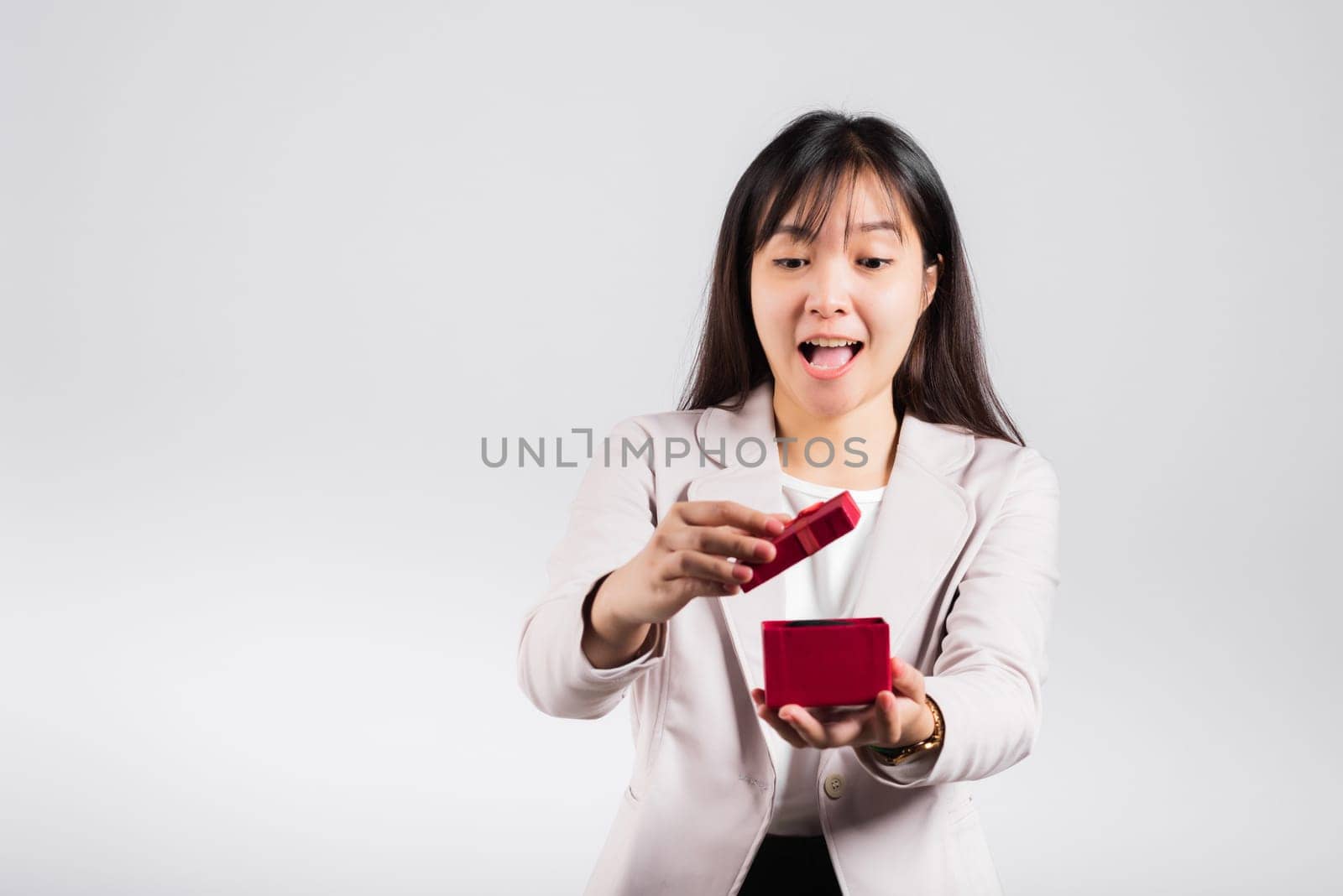 Smiling woman confidence opening a red gift box on palm isolated white background, surprise birthday or Christmas day and valentine, Asian happy portrait beautiful young female studio shot, copy space