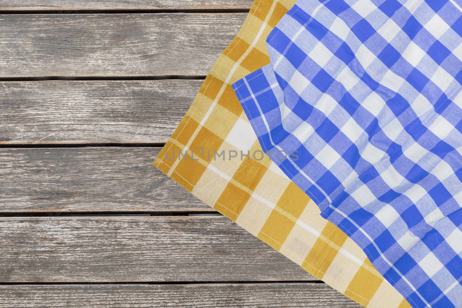 Empty table product. Top view of a rustic wooden table with a blue and a yellow checked tablecloth or napkin. Template for your food and product presentation montage. Space for food recipes.