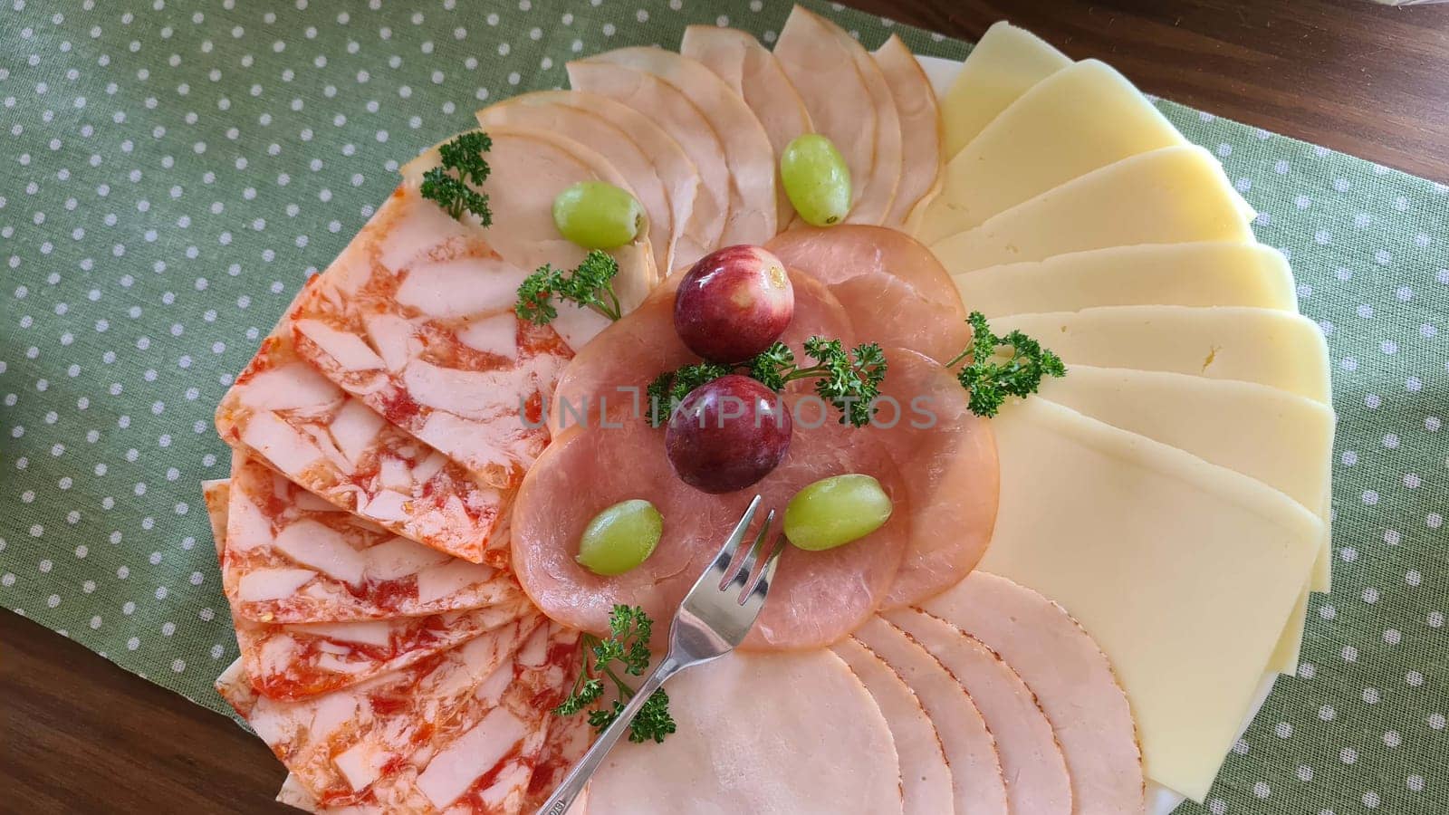 Food tray with delicious salami, pieces of ham, sausage, tomatoes, lettuce and vegetables - meat platter with selection - cut sausage and sausage on a celebratory table.
