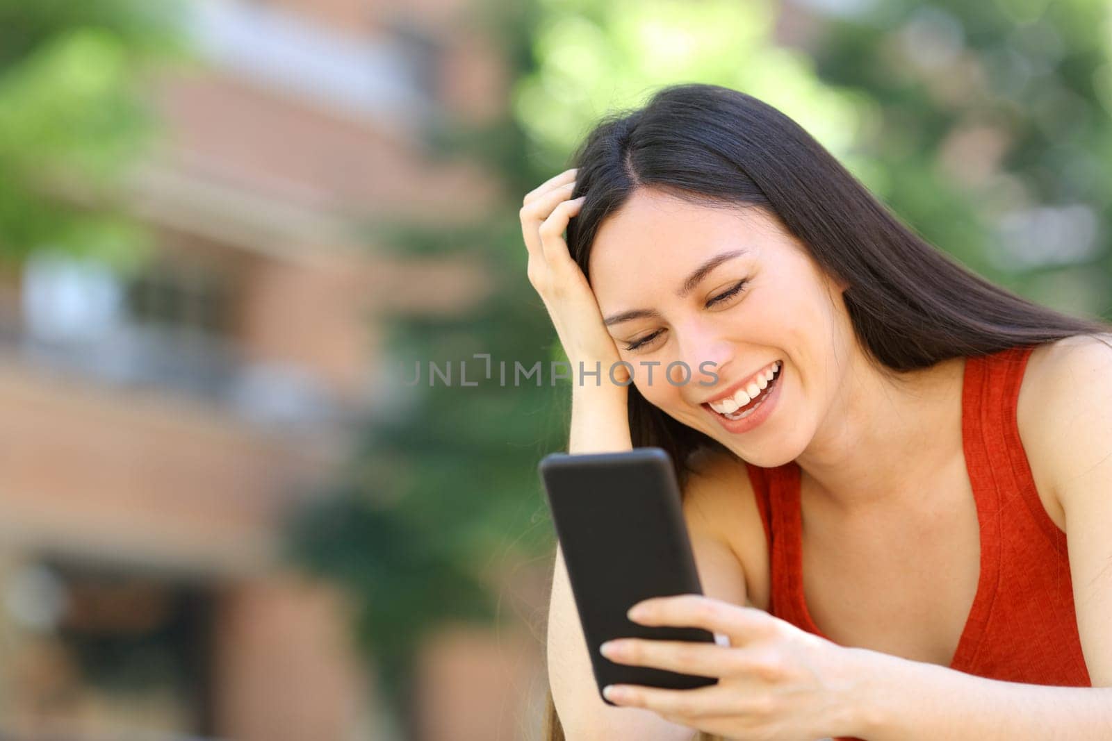 Happy asian woman checking phone message in the street