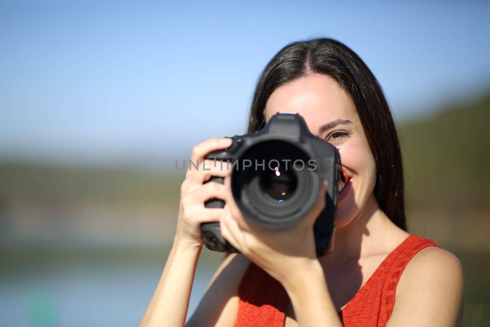 Happy woman taking photos with dslr camera in nature