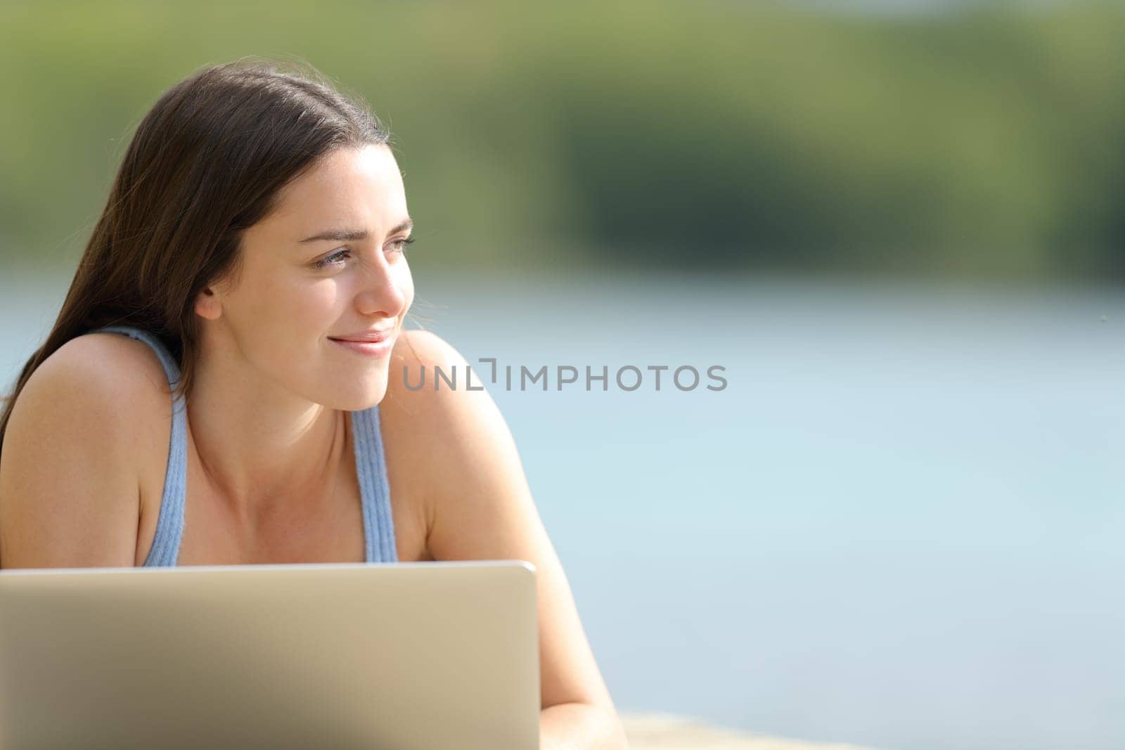 Happy woman with laptop looking at side in nature