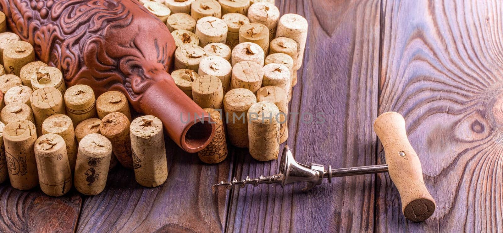 The Clay bottle, metal corkscrew and cork on a wooden table