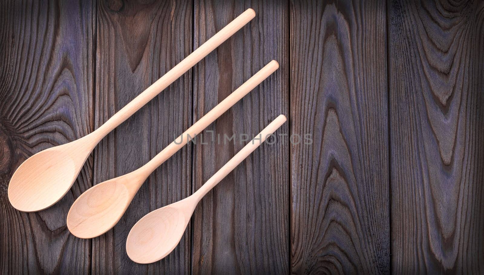 The three wooden spoons on a dark wood table with copy space