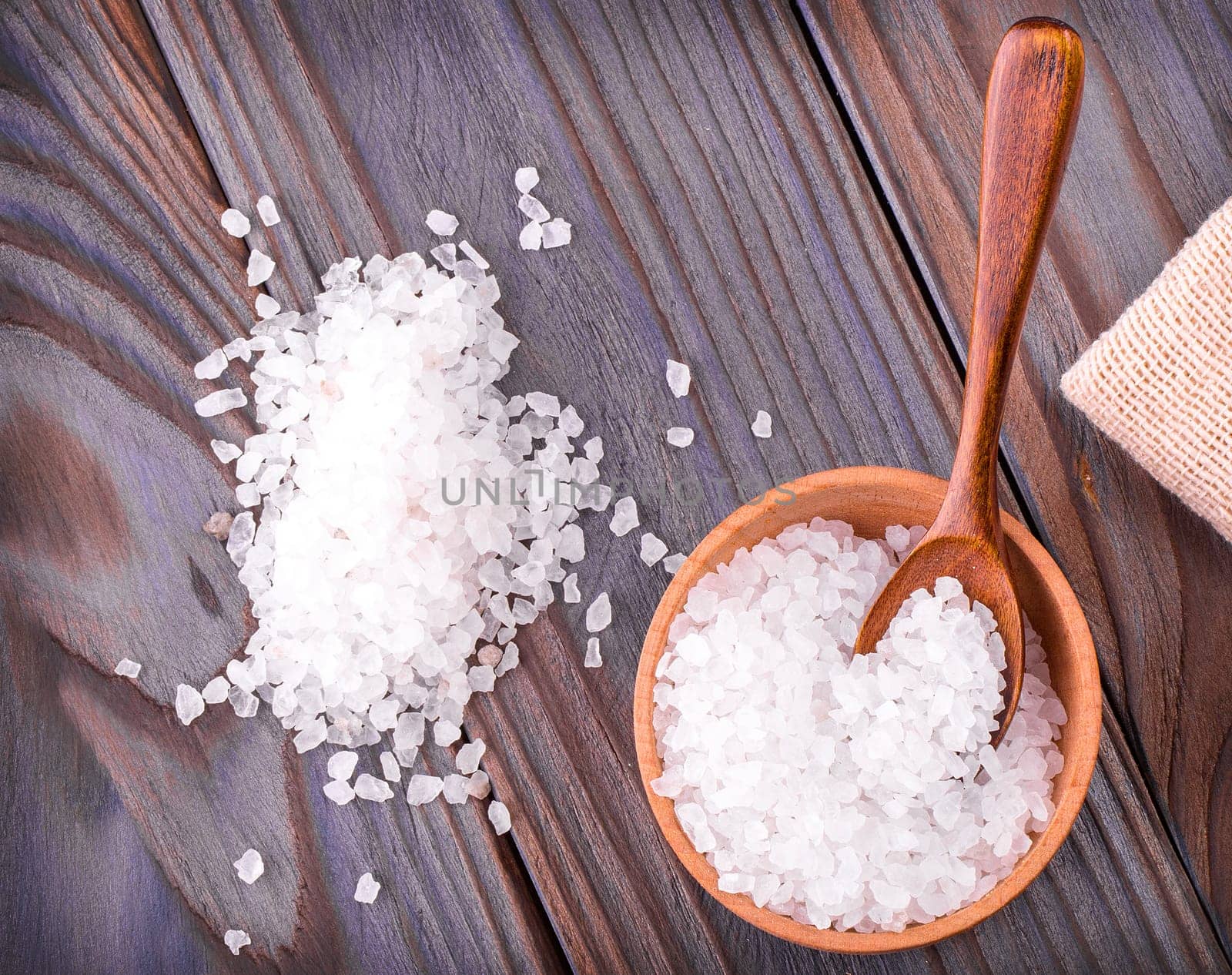 The Sea salt on cup, spoon and burlap on a wooden table