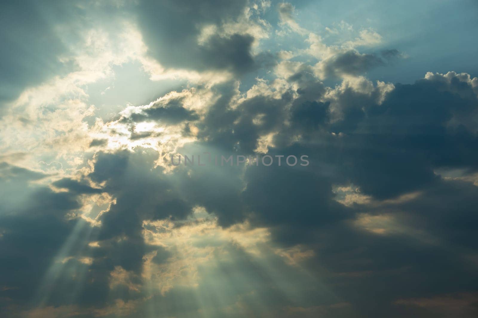 The sun behind the clouds and the sun's rays, summer day