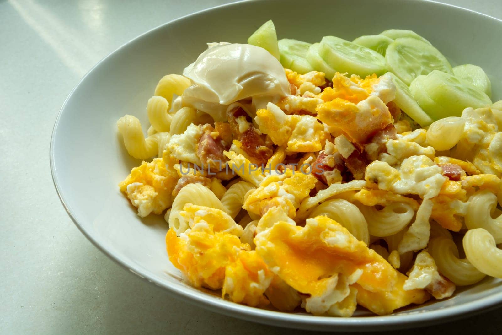 Scrambled eggs with bacon and mayonnaise in a white plate