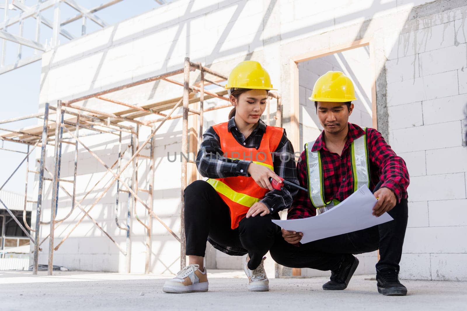 Architect and client discussing help create plan with blueprint of the building at construction site. Asian engineer foreman worker man and woman meeting talking on drawing paper project, team work