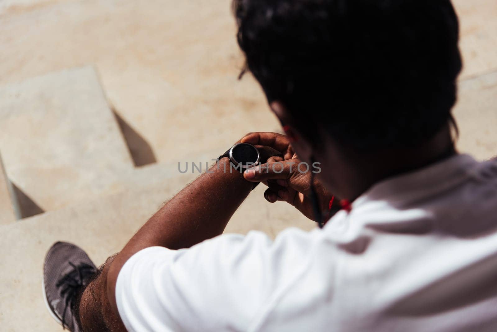 Close up Asian young athlete sport runner black man wear modern time smart watch he sitting resting before training running at the outdoor street health park, healthy exercise before workout concept